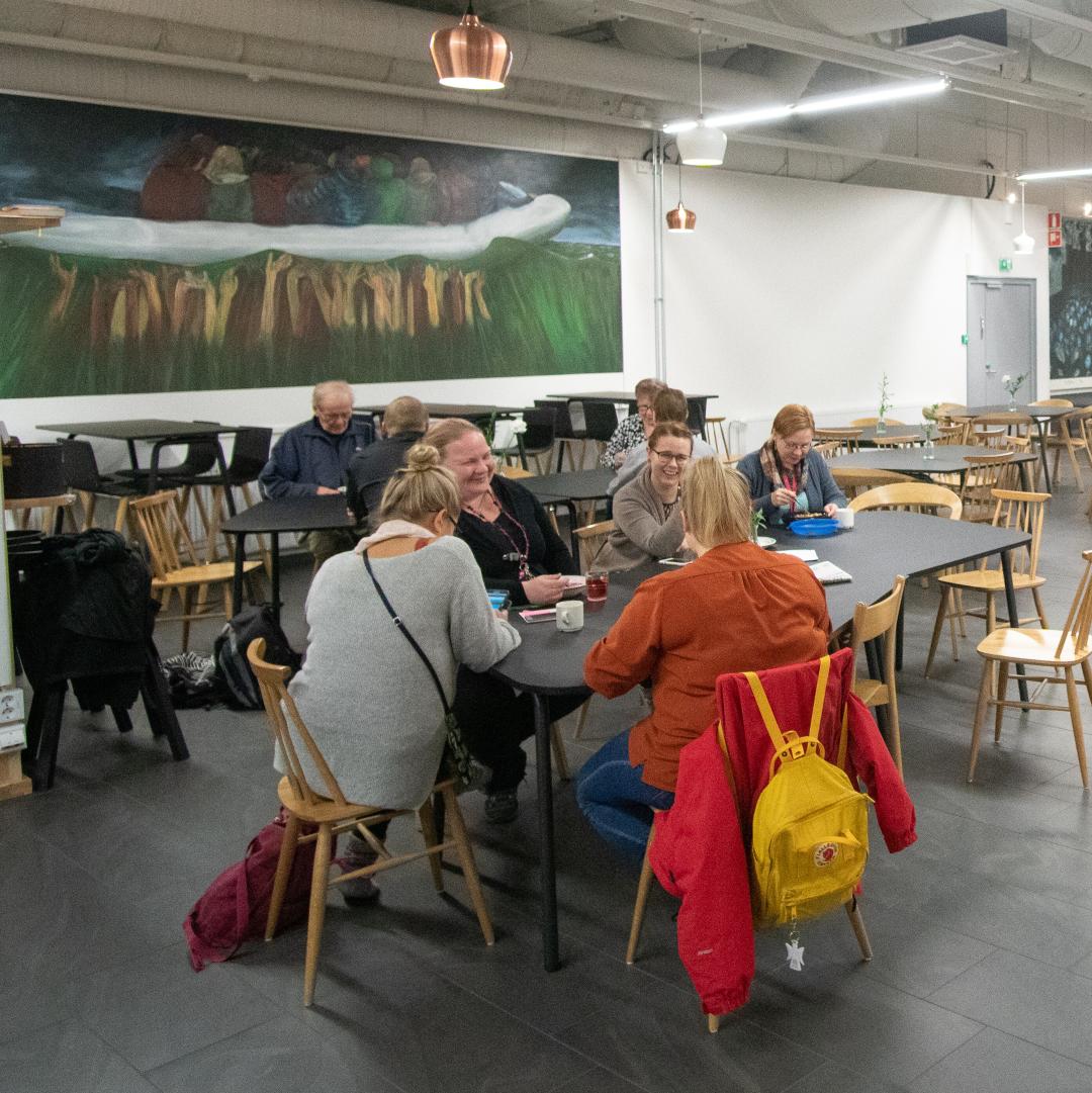 Näkymä Kipinän kahviosta, nojatuoleja ja pöytiä, ihmisiä istumassa pöytien ääressä