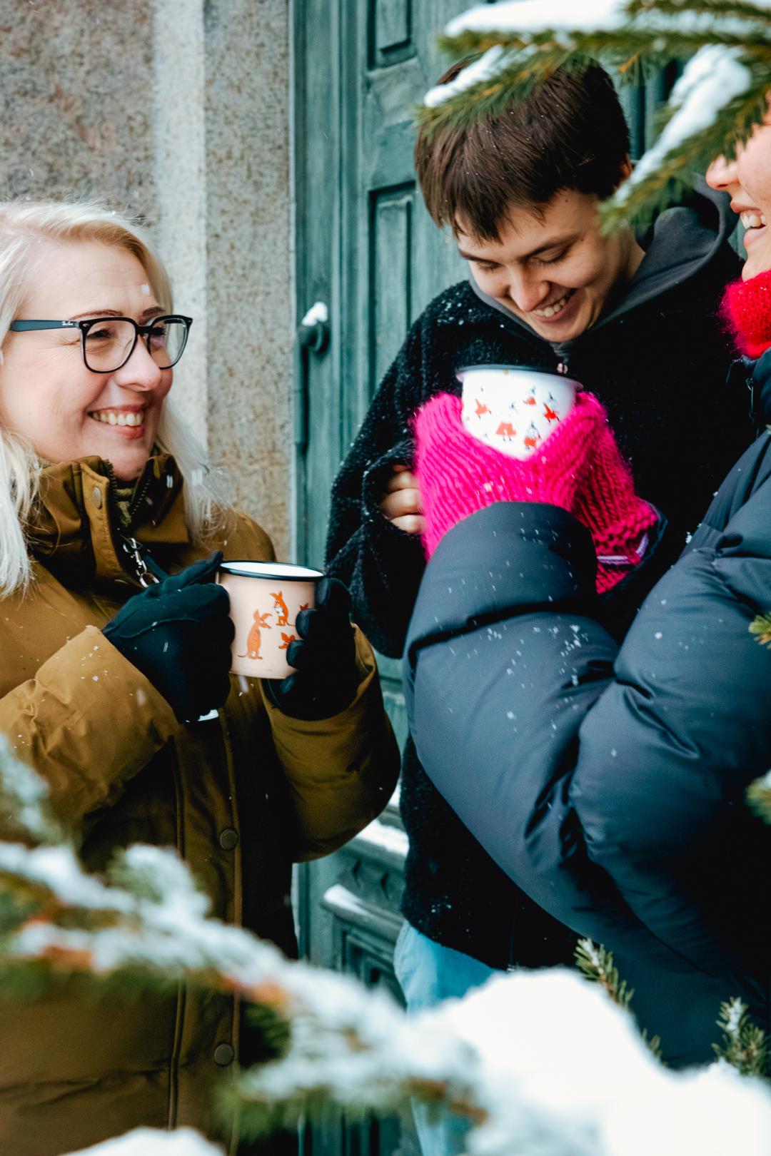 ihmisiä kirkon ovella kahvimukit kädessä